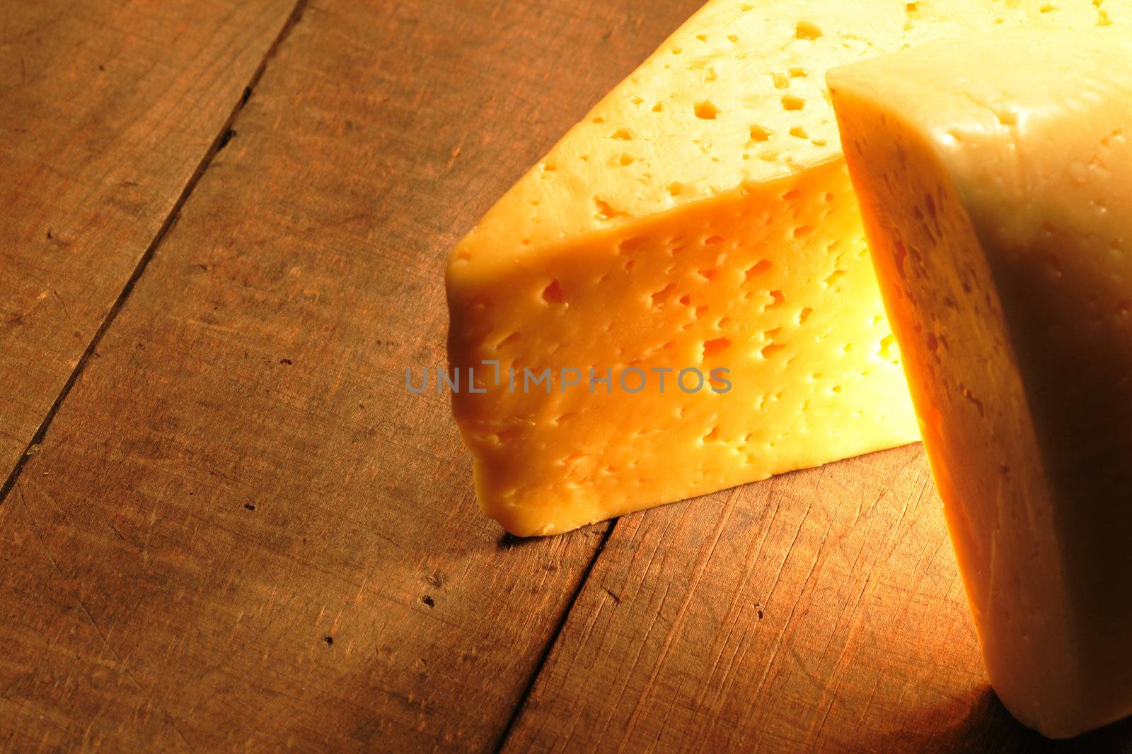 Two cheese pieces lying on wooden board. Nice lighting effect and copy space