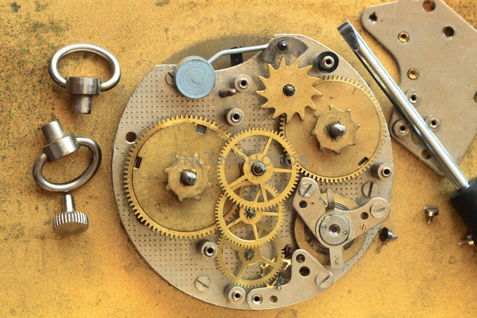 Closeup of disassembling alarm clock and screwdriver on yellow metal background