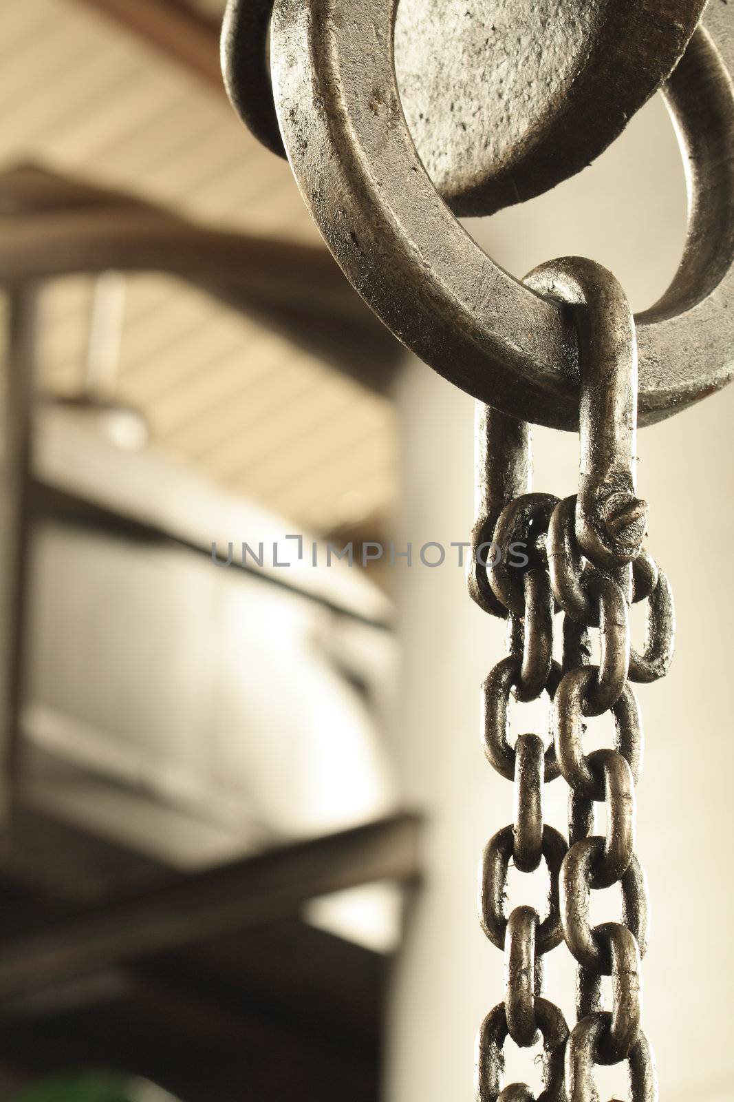 Closeup of steel chain fastening with metal ring hanging on crane hook
