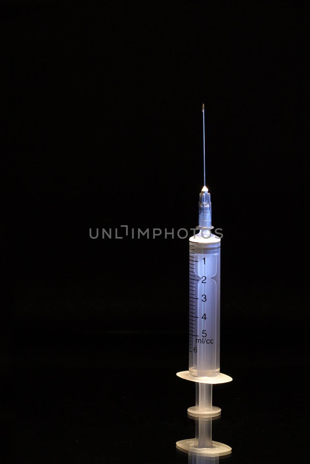 A plastic syringe with hypodermic needle on dark background