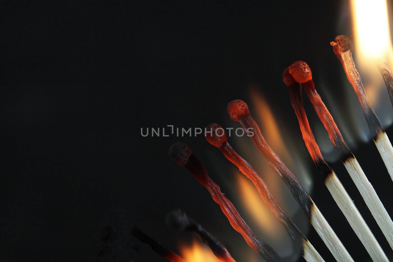 Closeup of few burning matches on dark background with copy space