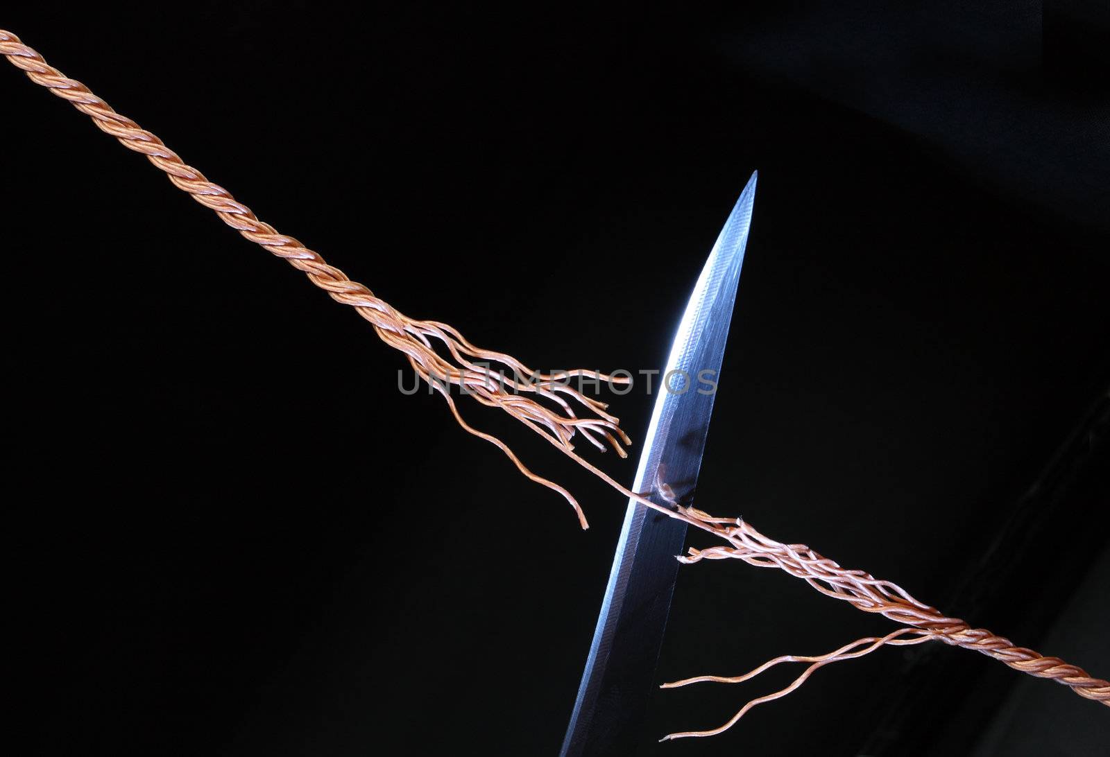 Sharp knife cutting rope on dark background with copy space