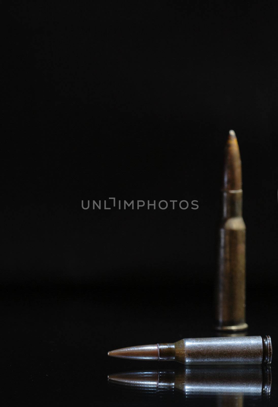 Two high power rifle cartridges on a dark background with copy space