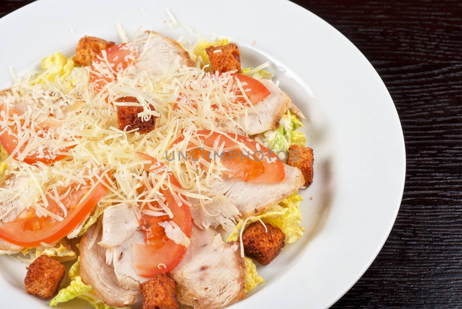 Salad of lettuce, chinese cabbage, tomato, garlic rusk, parmesan cheese, sauce and chicken meat