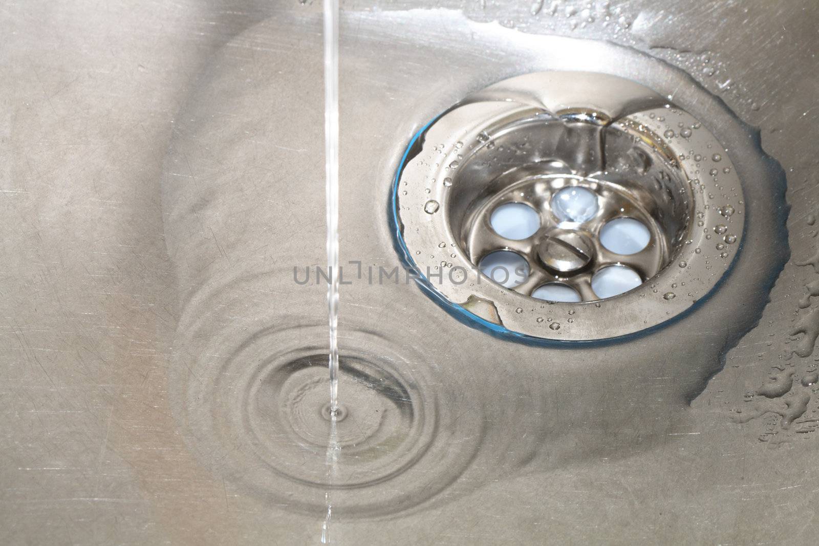 Closeup of gray stainless steel kitchen sink with water drops
