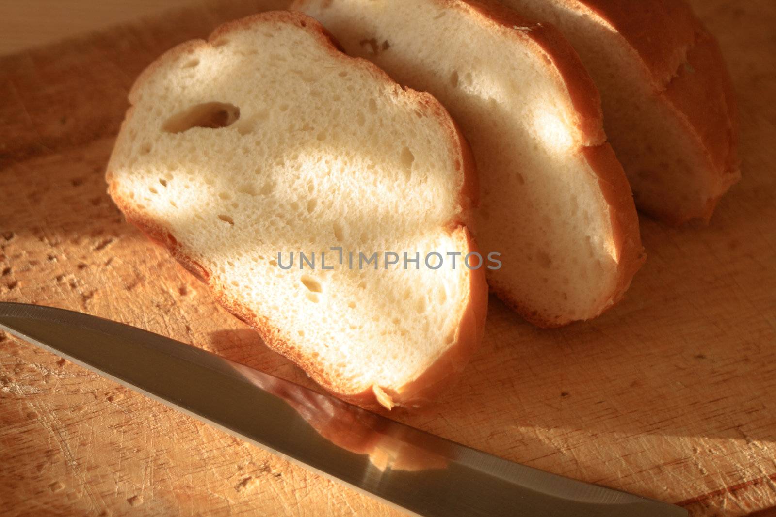 Sliced wheat bread and kitchen knife lying on wooden board