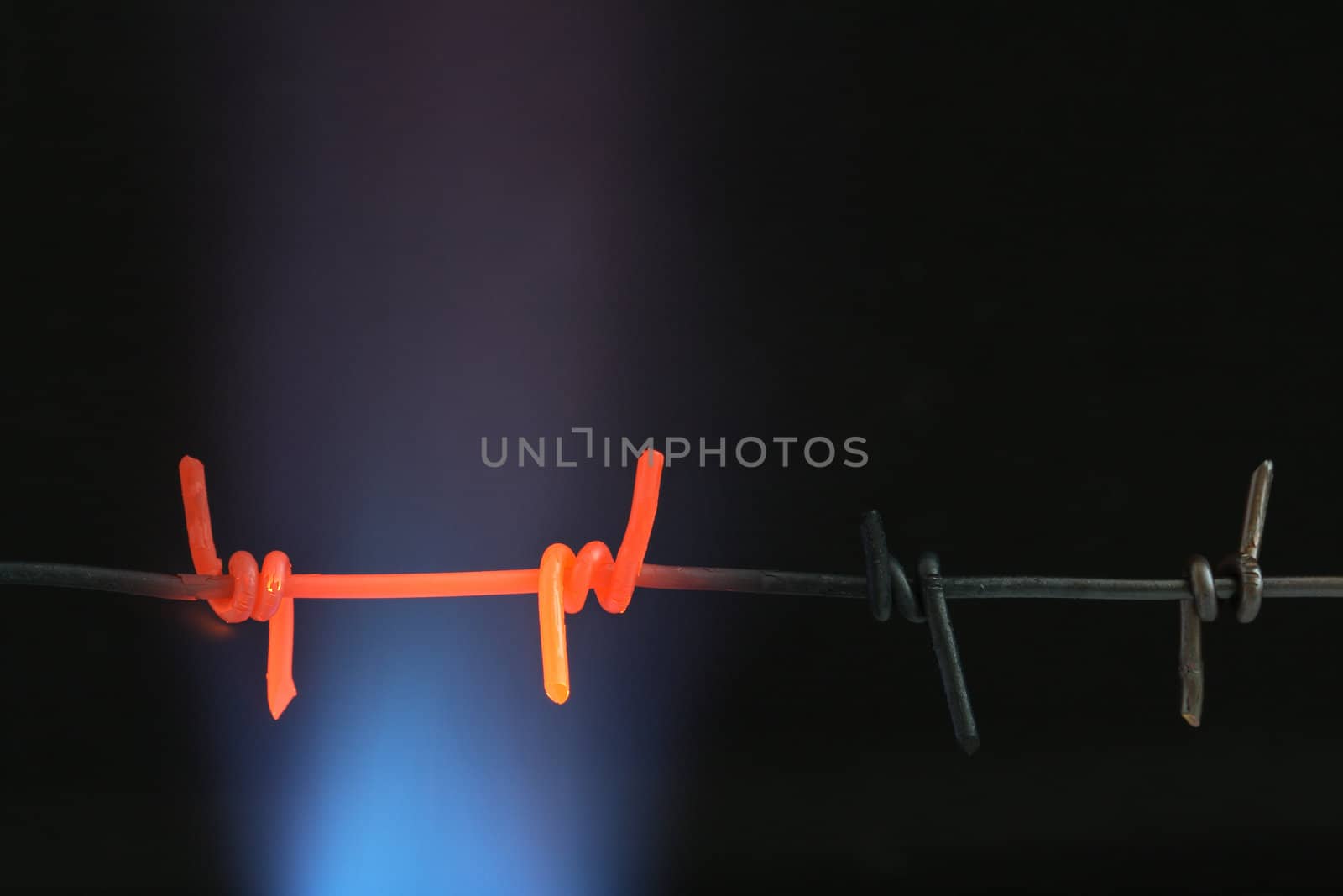 Abstract dark background with closeup of red-hot barbed wire