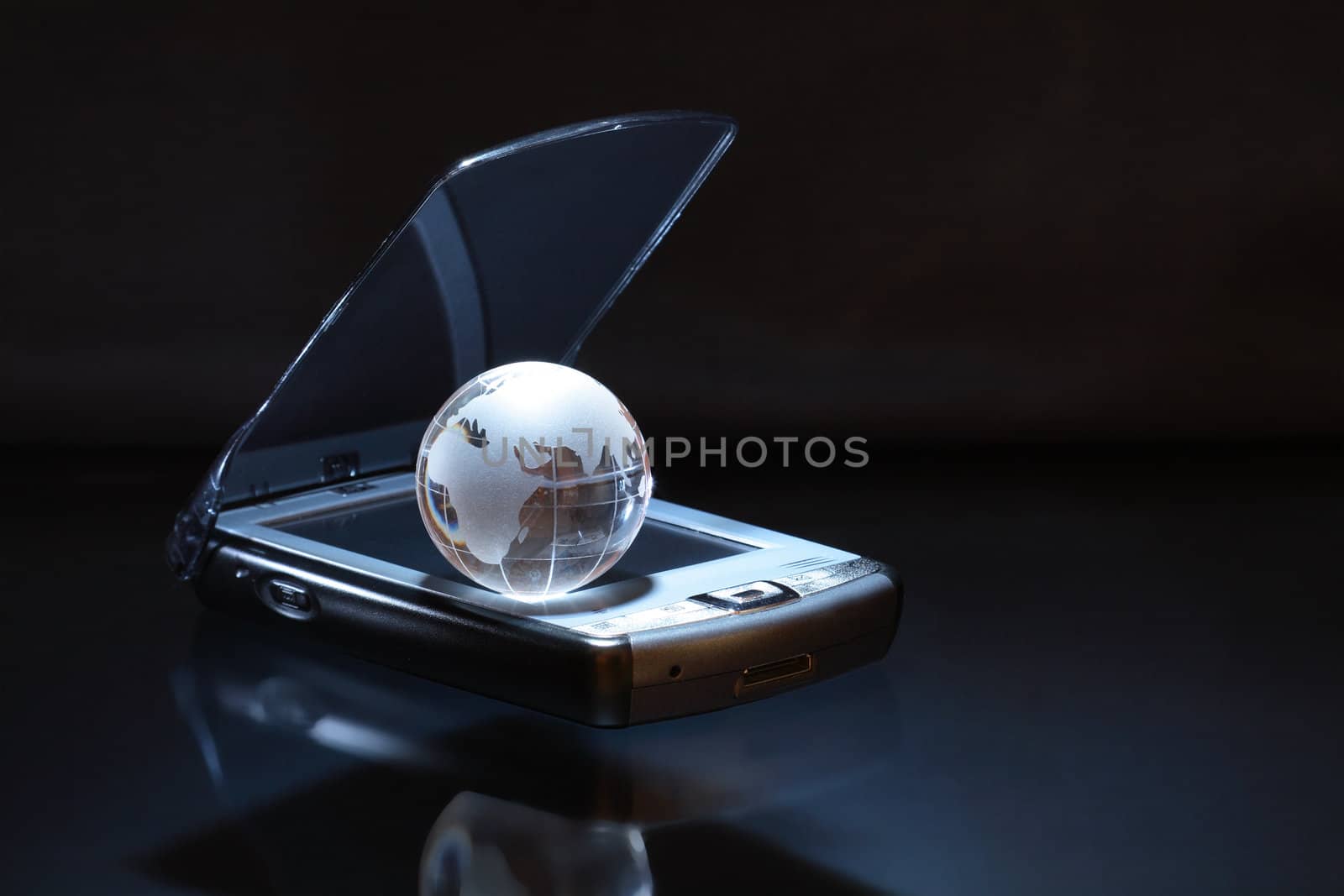 Glass globe lying on modern personal date assistant on dark background