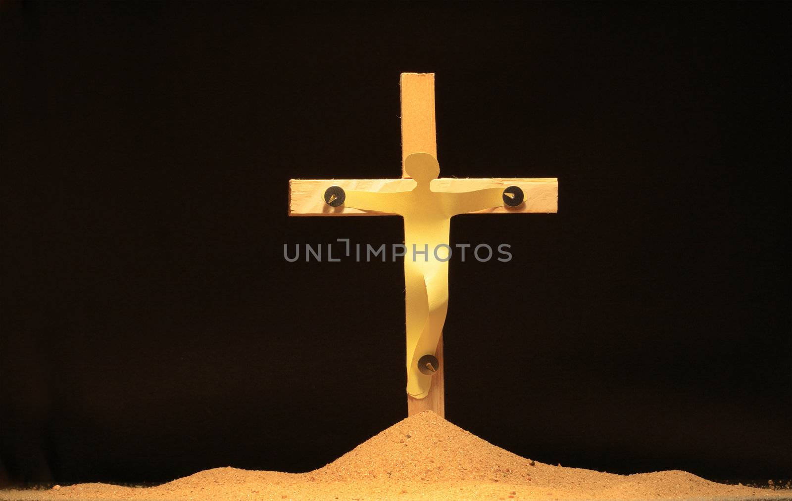 Paper man hanging on wooden cross woth thumbtacks on black background