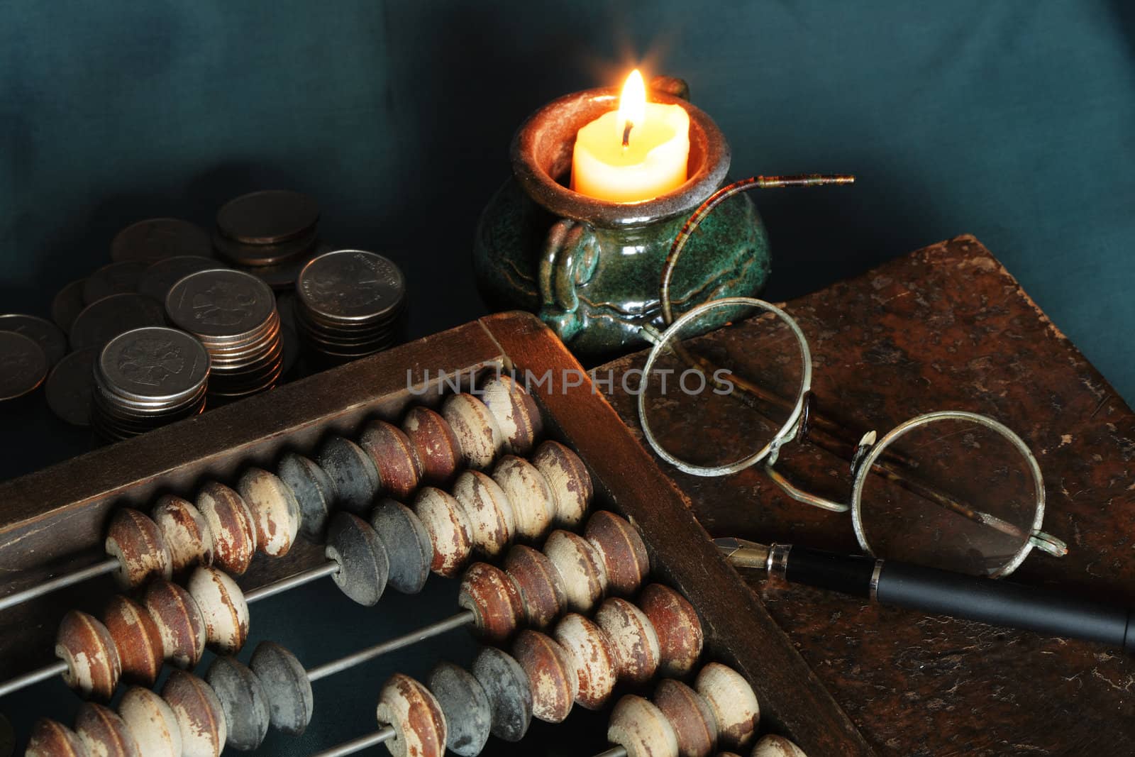 Vintage still life with candle and old things: counting frame, coins, book, spectacles