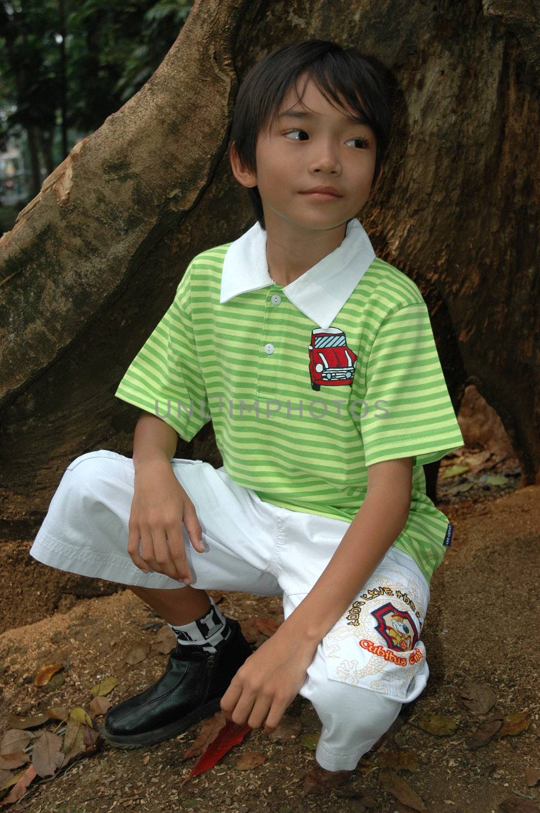 photograph of little asian boy sit down in park