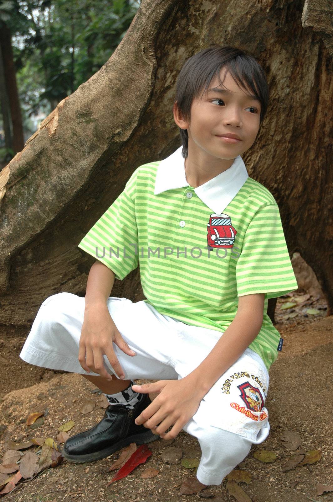 photograph of little asian boy sit down in park