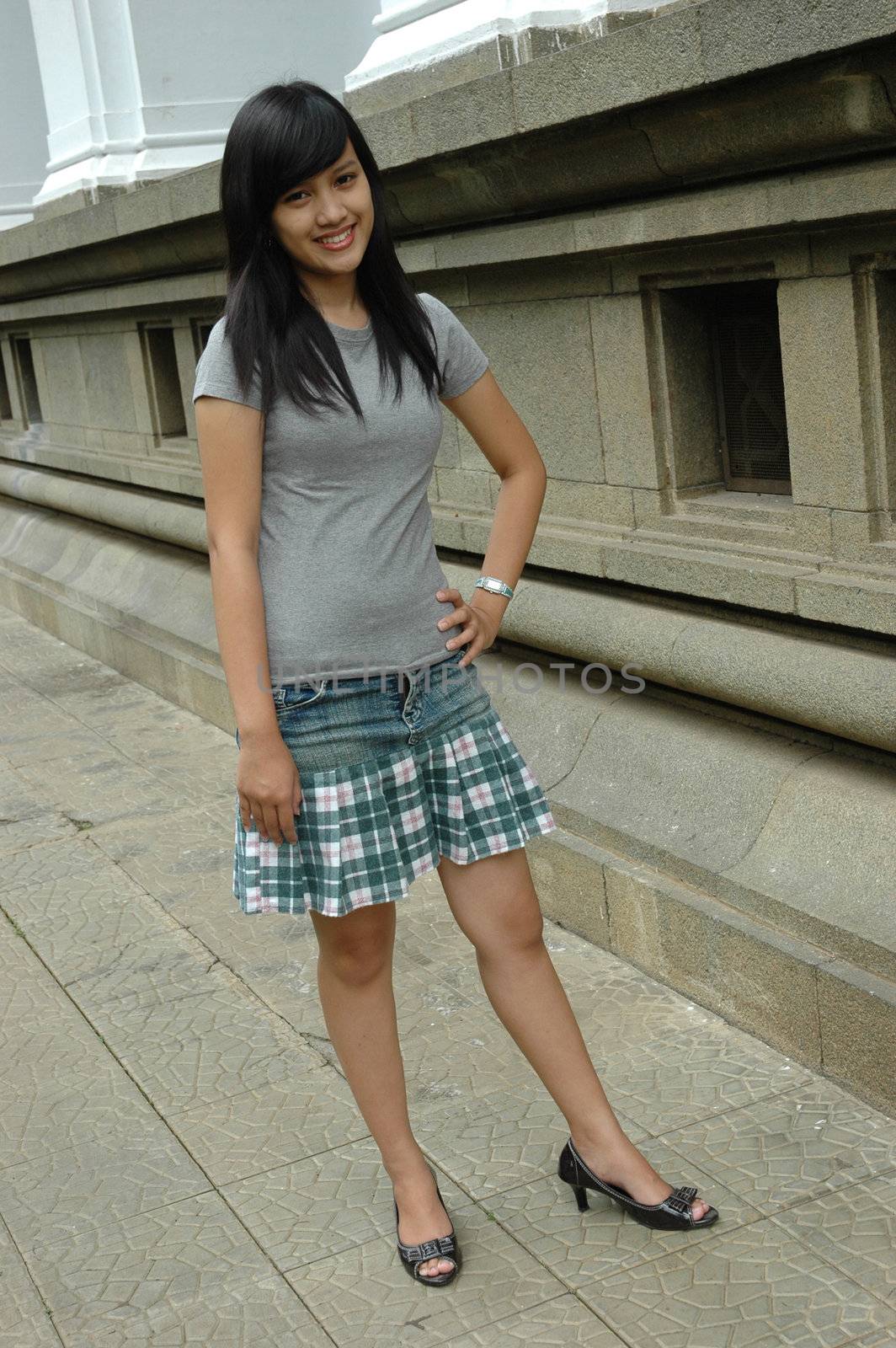young asian lady stand up beside solid rock wall
