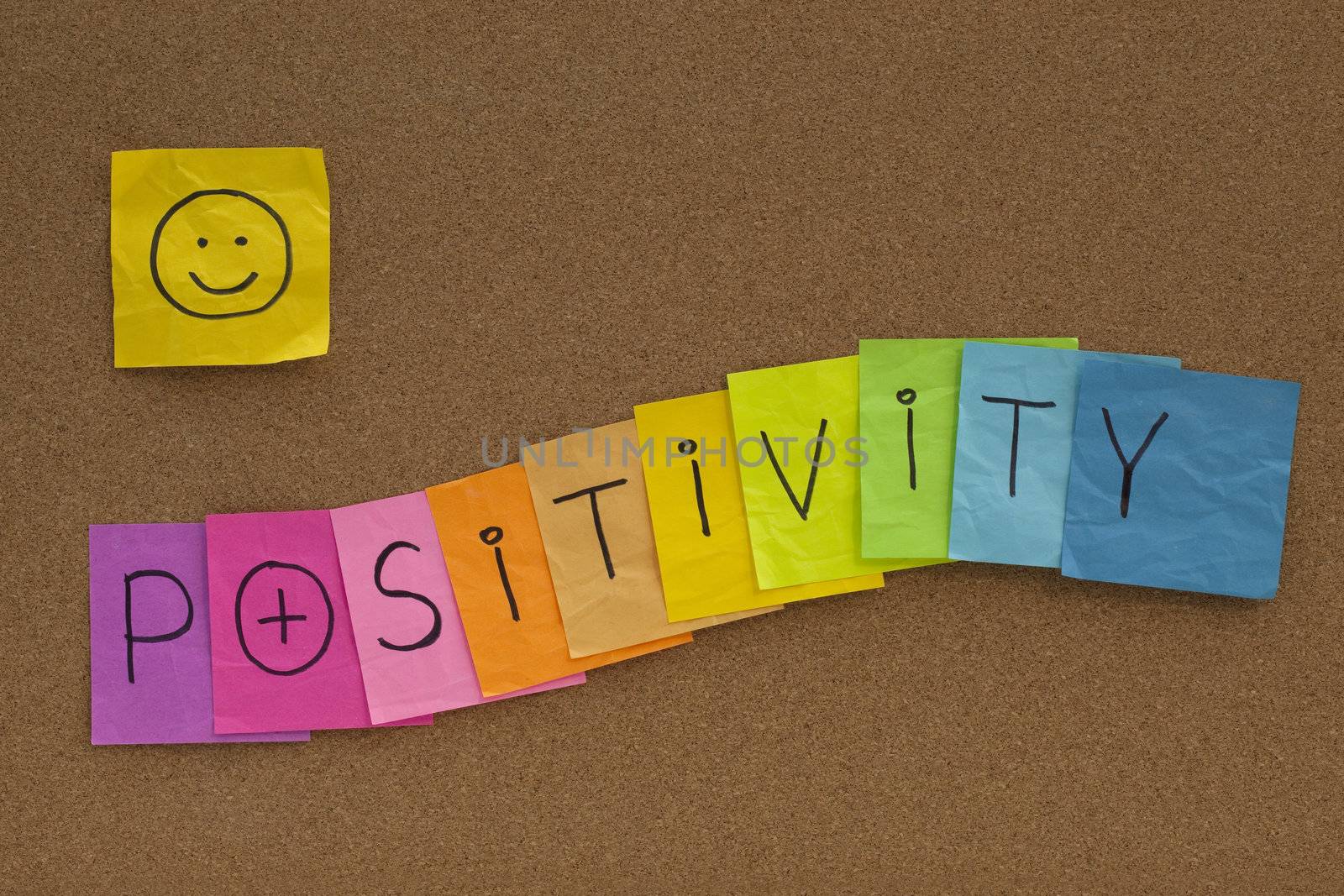 positivity concept on cork bulletin board - colorful sticky notes with a smiley