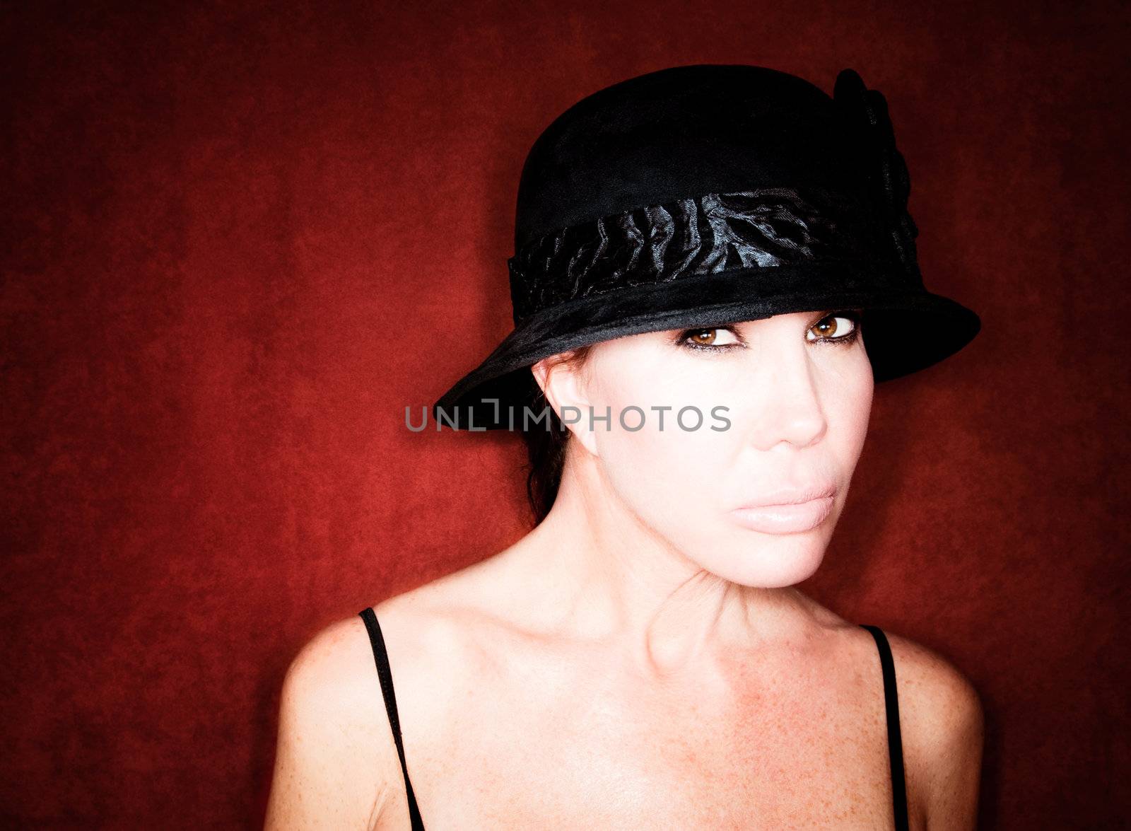 Beautiful woman in black hat against red background