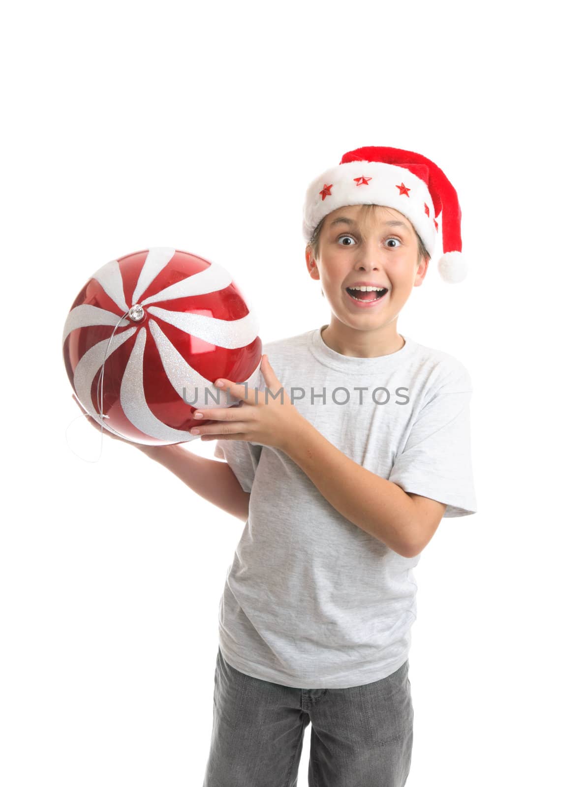 An excited ecstatic boy holding a big Christmas bauble ball decoration.  Red and white with sparkling glitter and a silver thread
