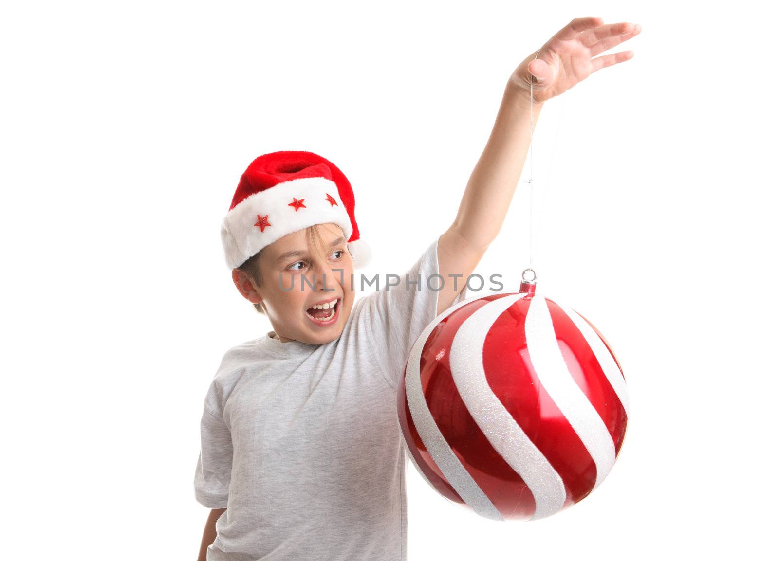 A enchanted child holding an oversized red and white swirled Christmas decoration in his hand.  
