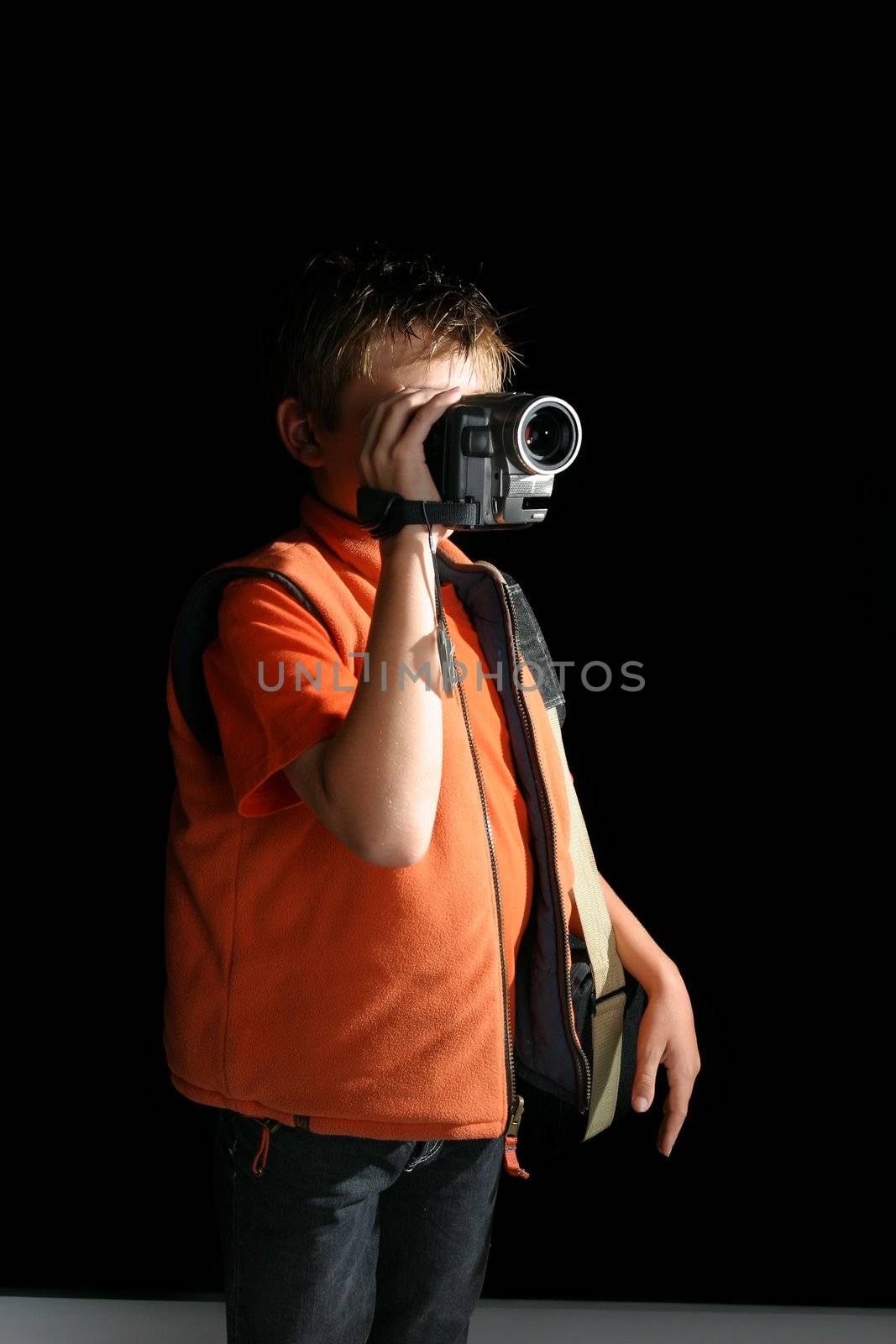 A child standing in a room or studio using a handheld digital video camera