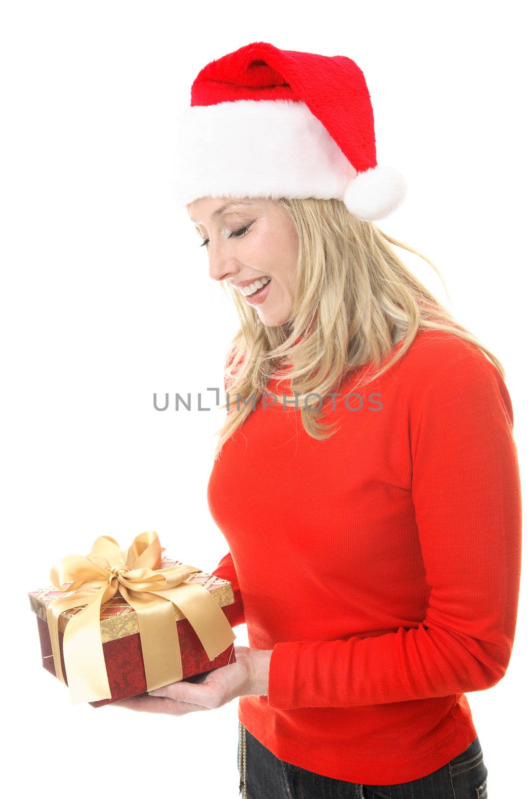 A smiling woman receiving a Christmas gift.   She is looking down and smiling in appreciation.