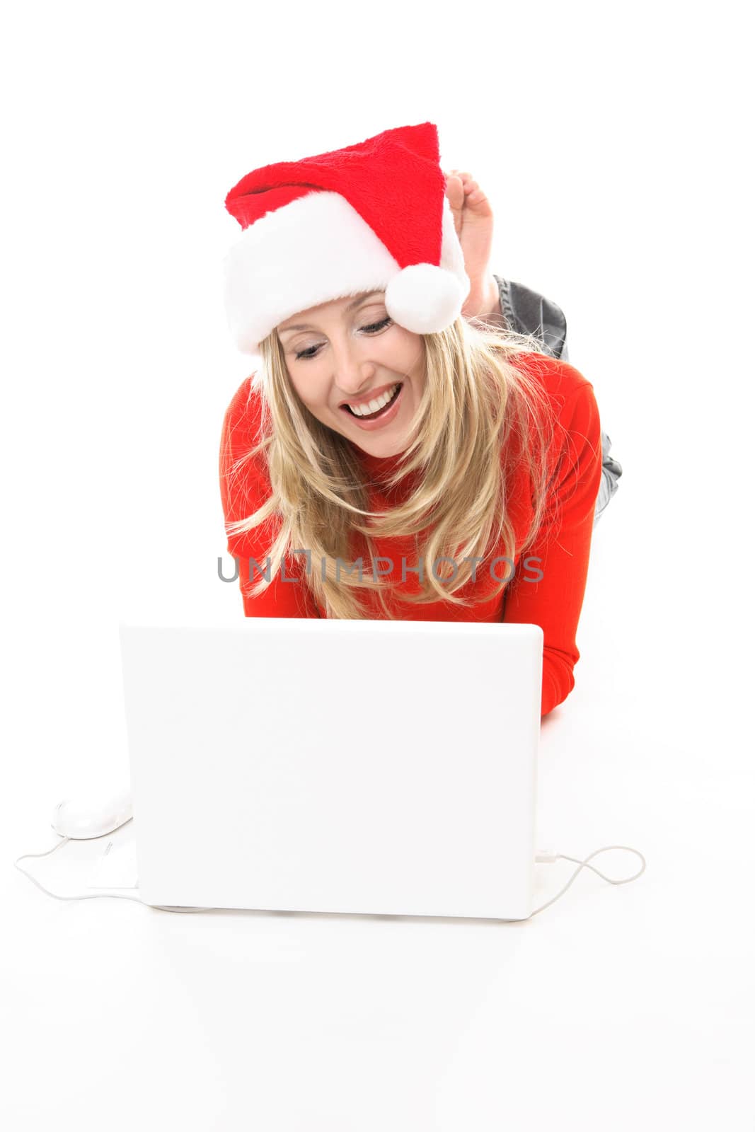 Christmas girl using a laptop to shop or browse the web online. She might also be studying chatting to friends or family  or electronic banking, etc.    She is wearing a festive santa hat and smiling.