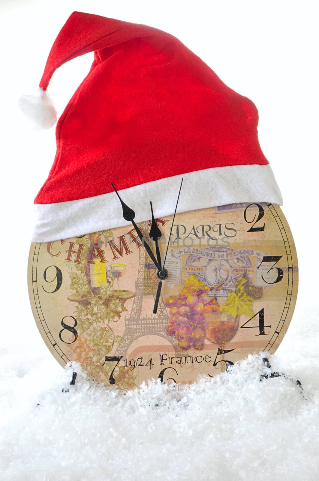 Clock in the hat of Santa Claus on a white snow background