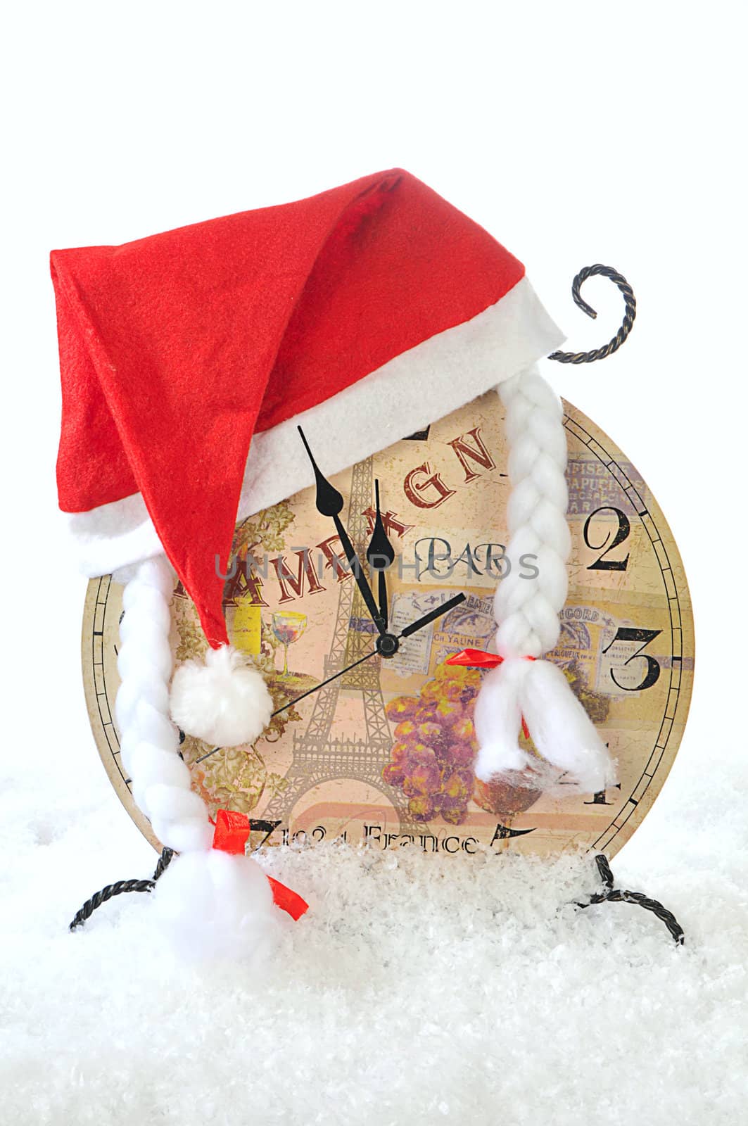 Clock in the hat of Santa Claus on a white snow background