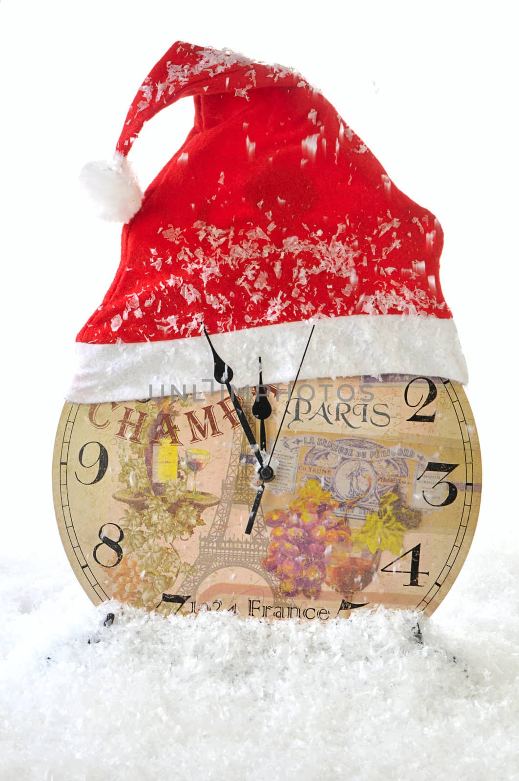 Clock in the hat of Santa Claus on a white snow background