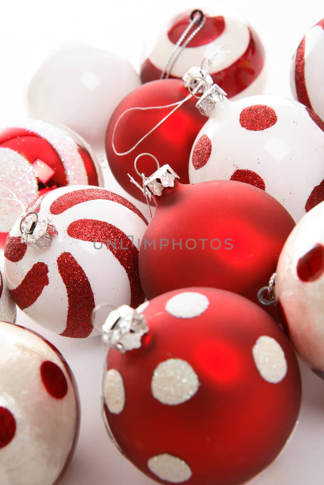 Various Christmas baublesin red and white theme colours sit  on a white background.  Focus to centre balls.