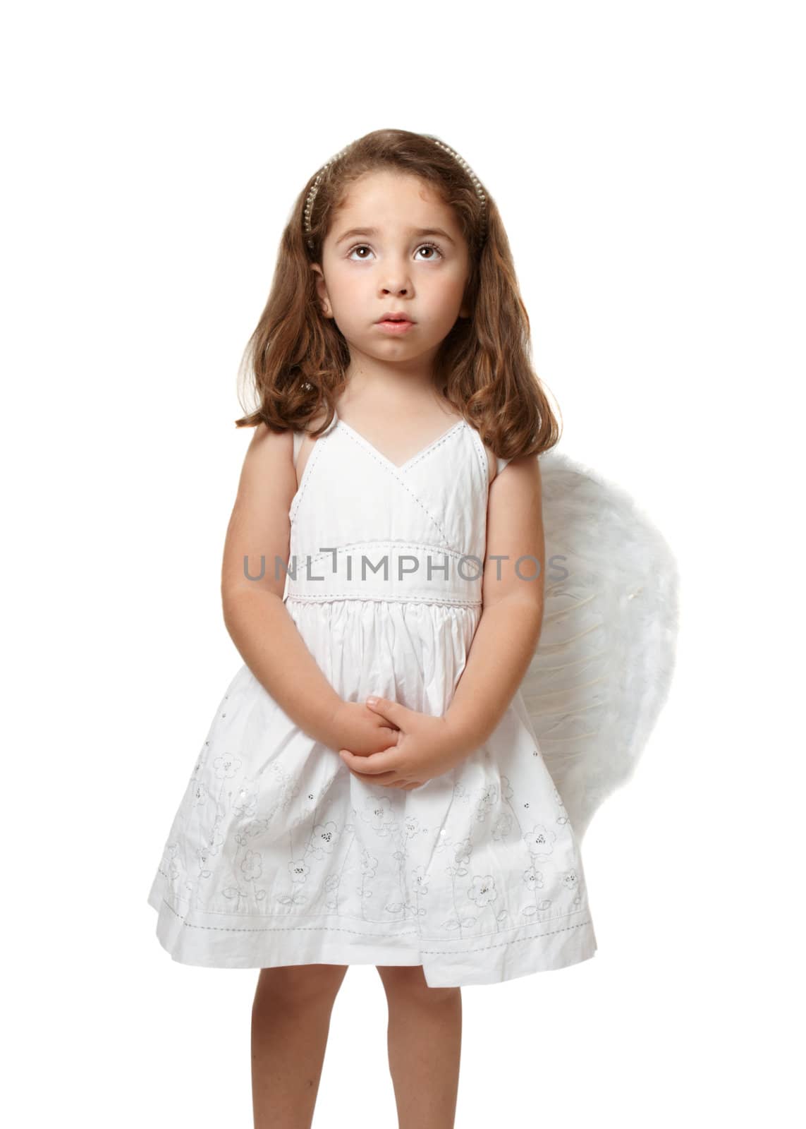 Little angel girl wearing a beautiful white embroidered dress.  She has her hands gently clasped and is looking up toward heaven or sky