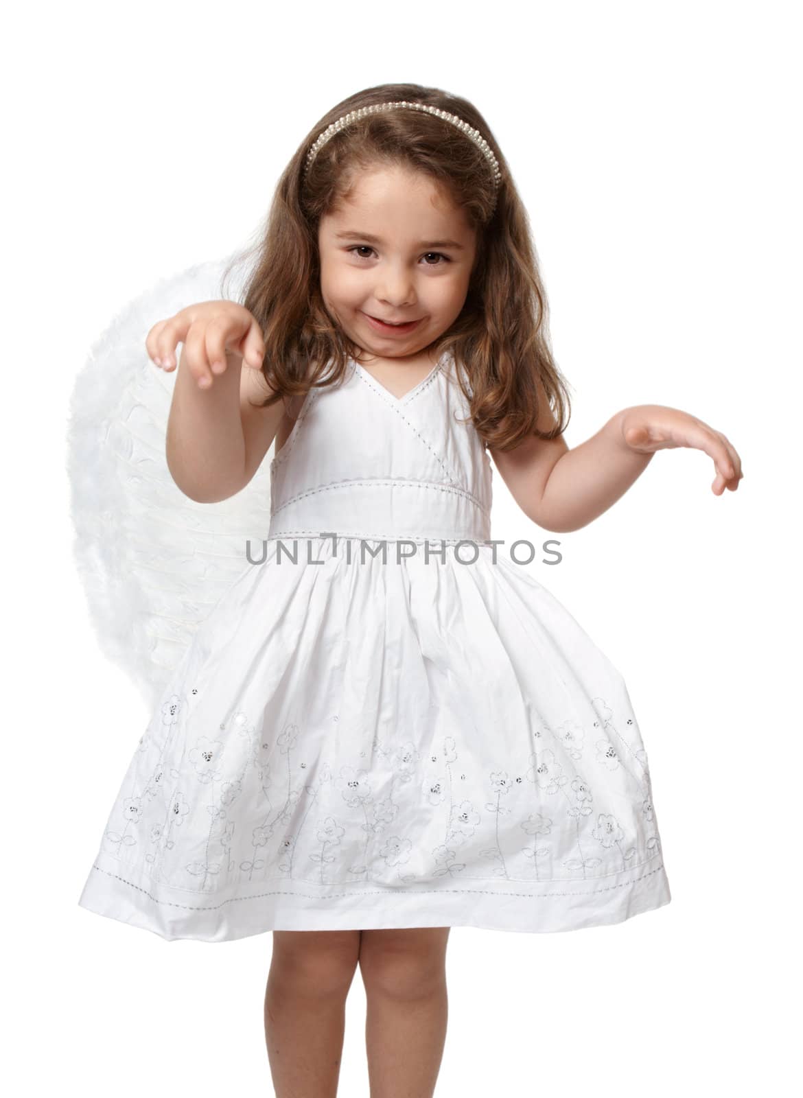 Angelic young preschool child in a pretty white dress with flower embroidery and she is wearing feather fairy angel wings