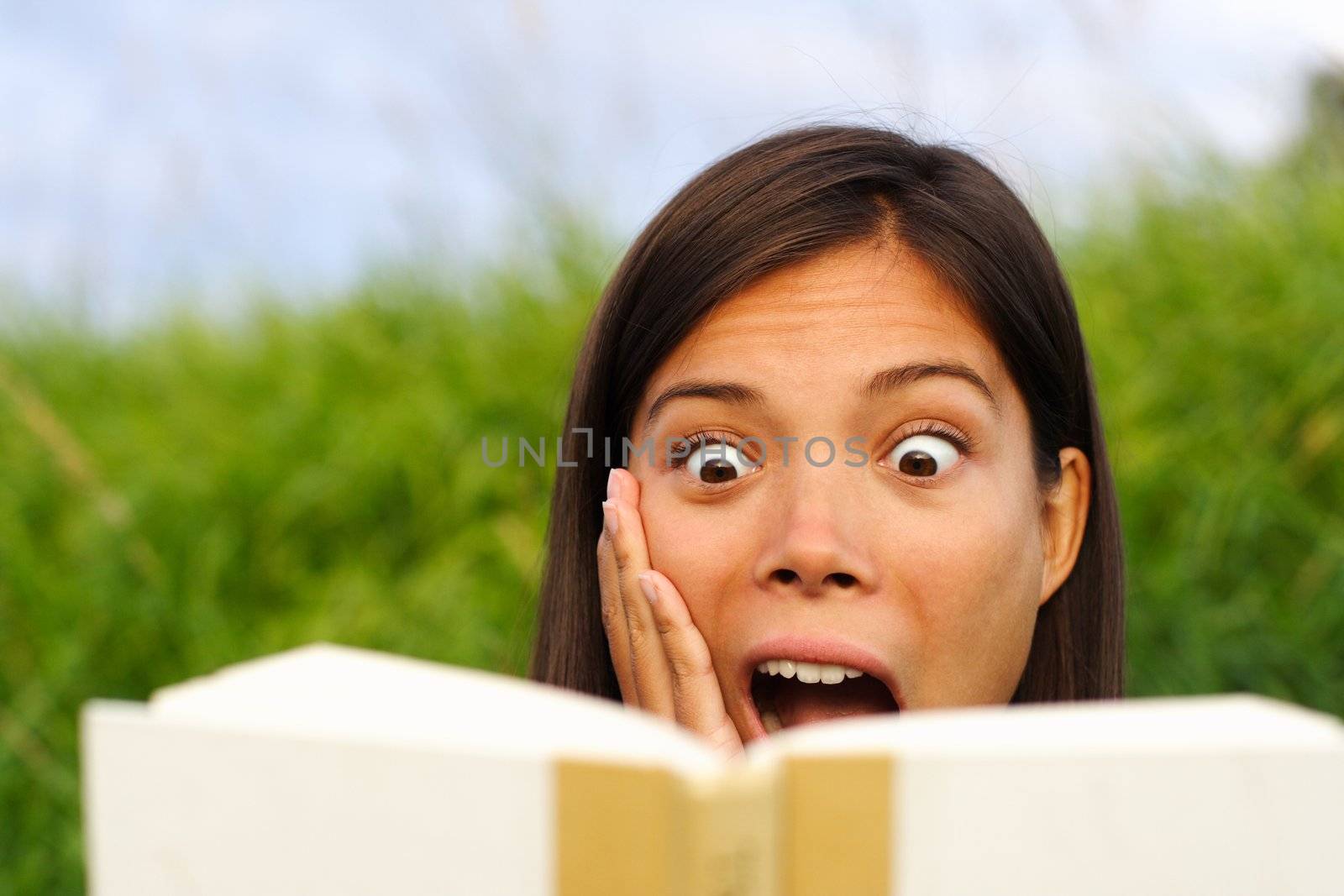 Shocked woman reading book by Maridav