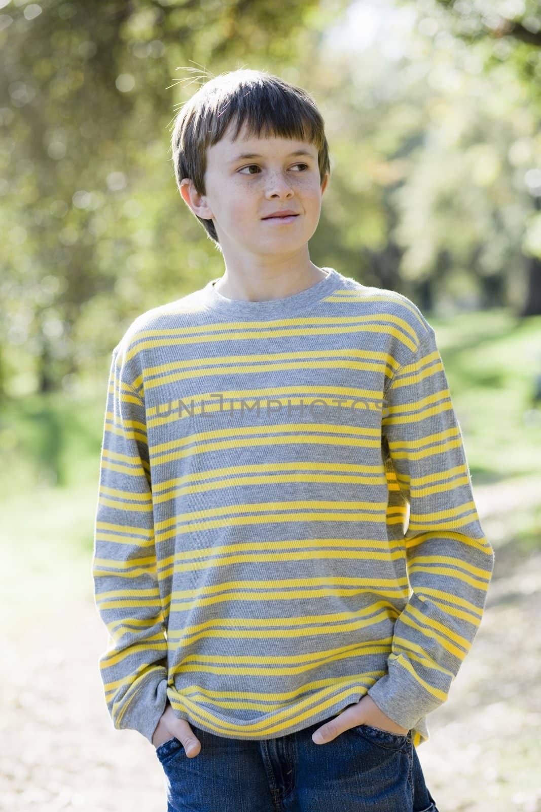 Cute Young Boy Standing Outdoors With Hands in Pockets