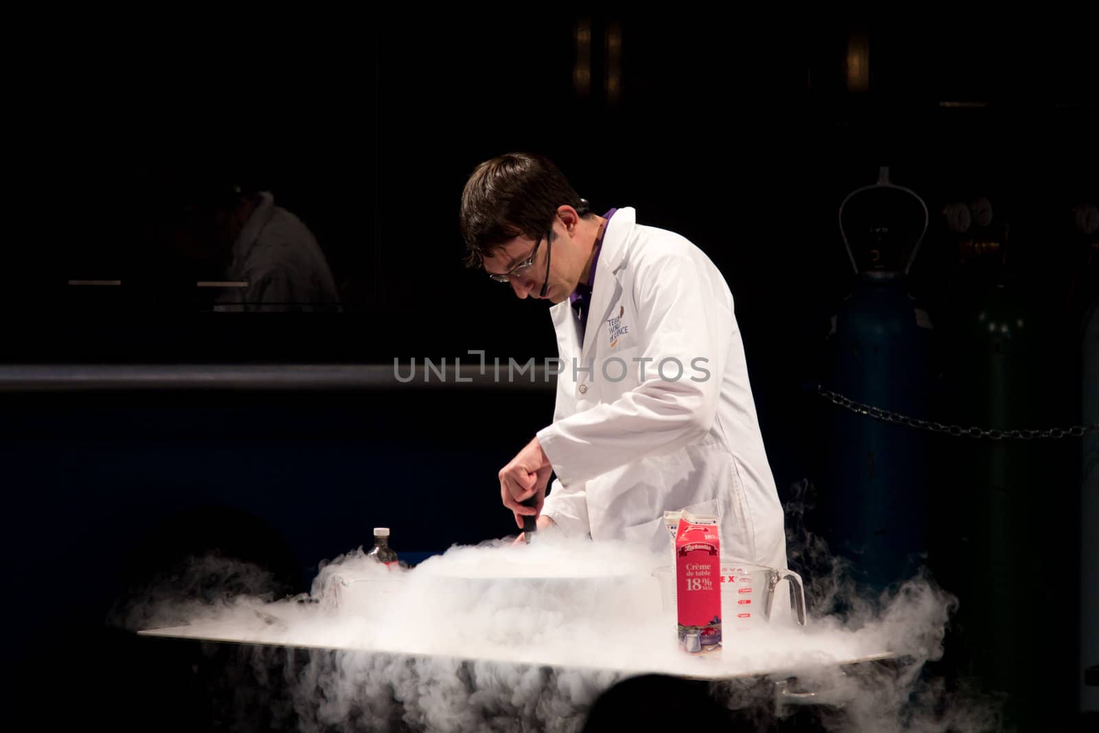 A scientist conducting an experiment to make ice cream out of cream using liquid nitrogen which is forming a white smoke of cold gas as it vaporizes.