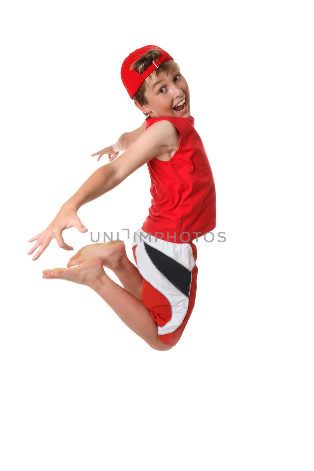 A happy boy full of vitality jumps off the ground with hand and legs back