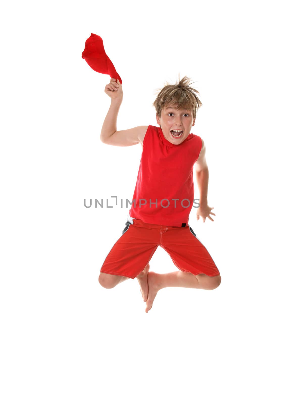 A boy with zestful energy jumps high off the floor and takes off his hat.