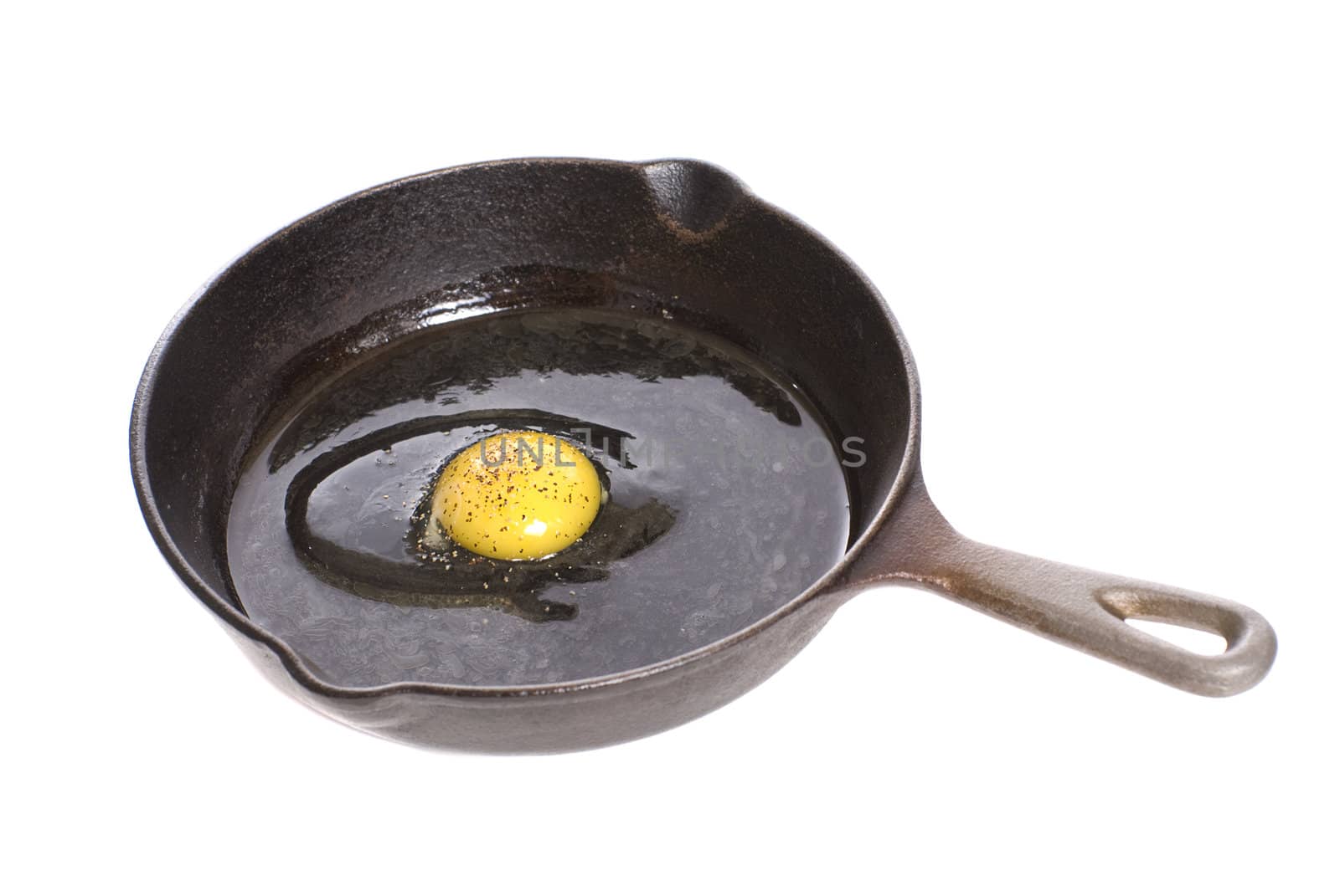 A peppered egg shot in a black pan, isolated against a white background