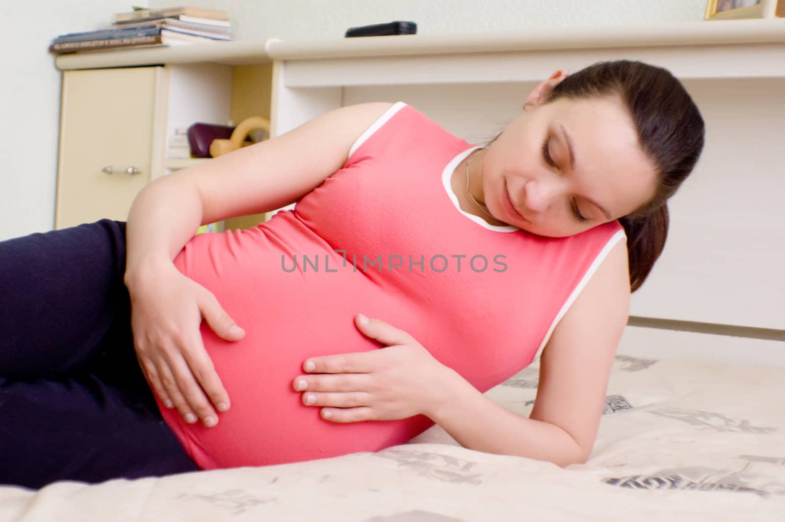 Pregnant woman lying on bed and thinking