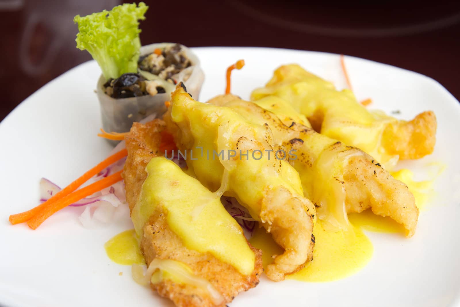 baked fish fillets with cheese sauce served in a white plate