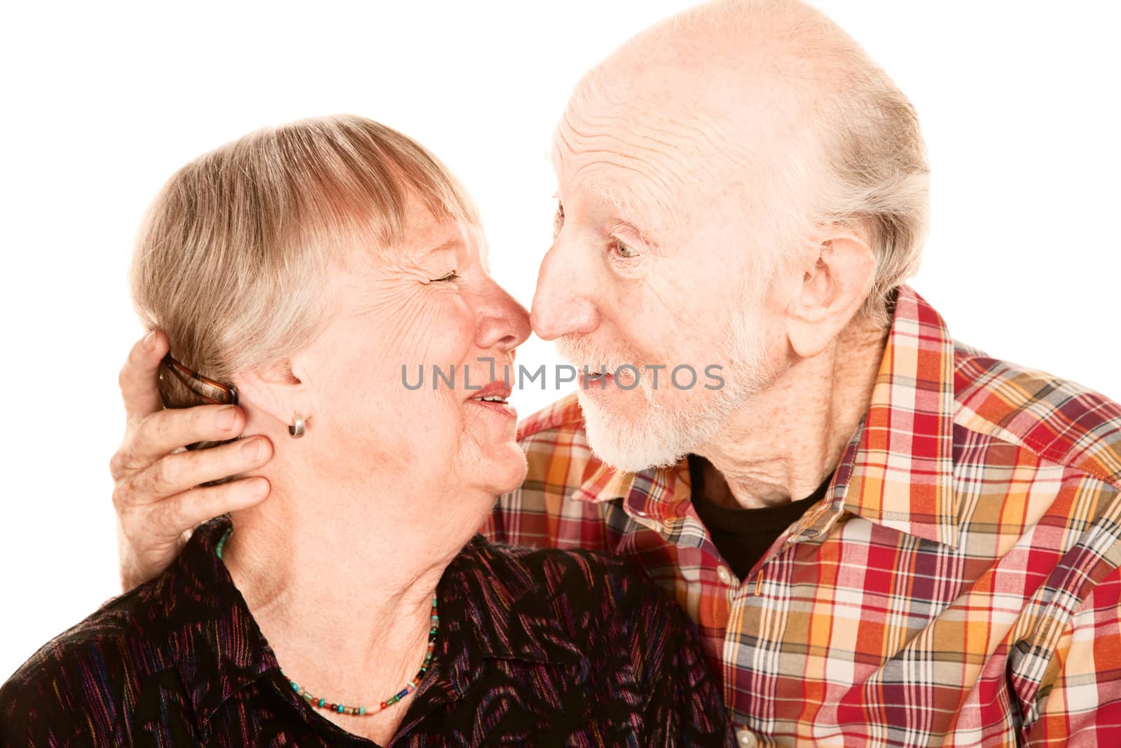 Smiling senior couple touching their noses together and leaning in to kiss