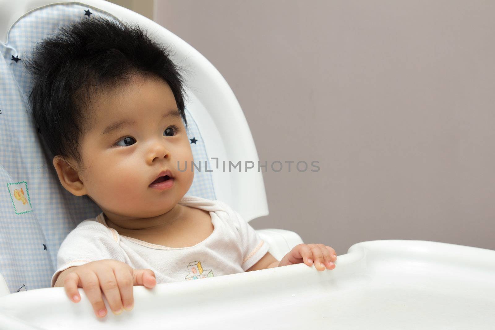 Portrait of a little Asian baby girl sits on a high chair