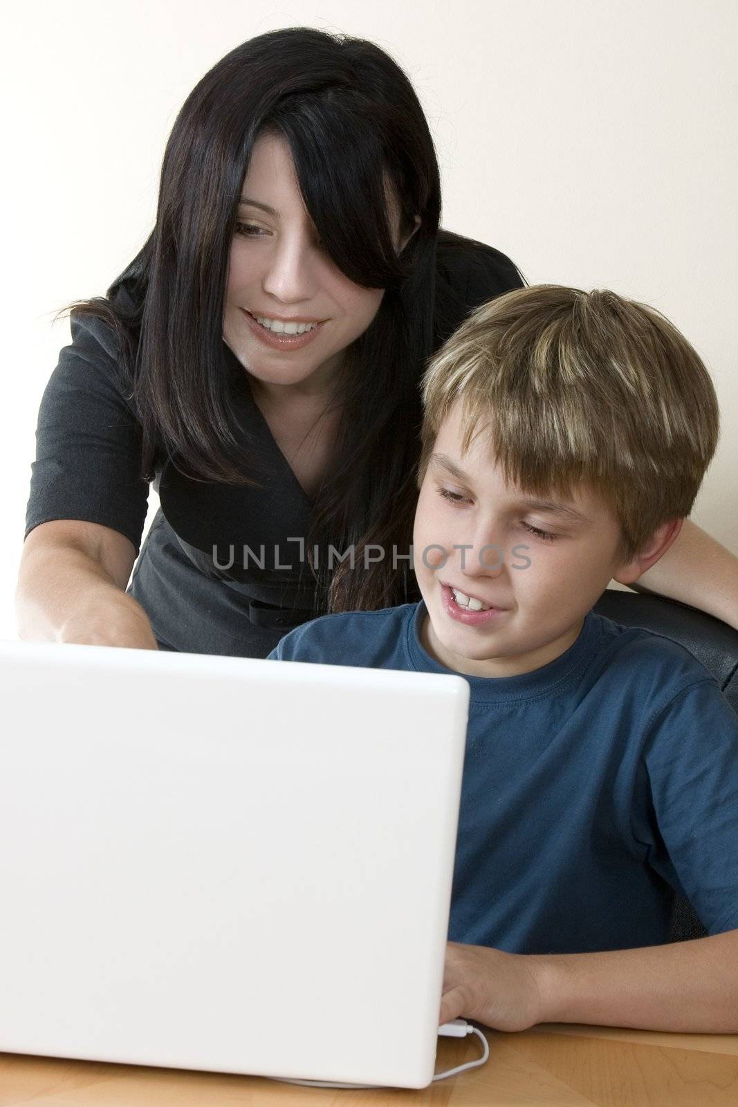 Adult woman helps a child sitting at the laptop computer.
