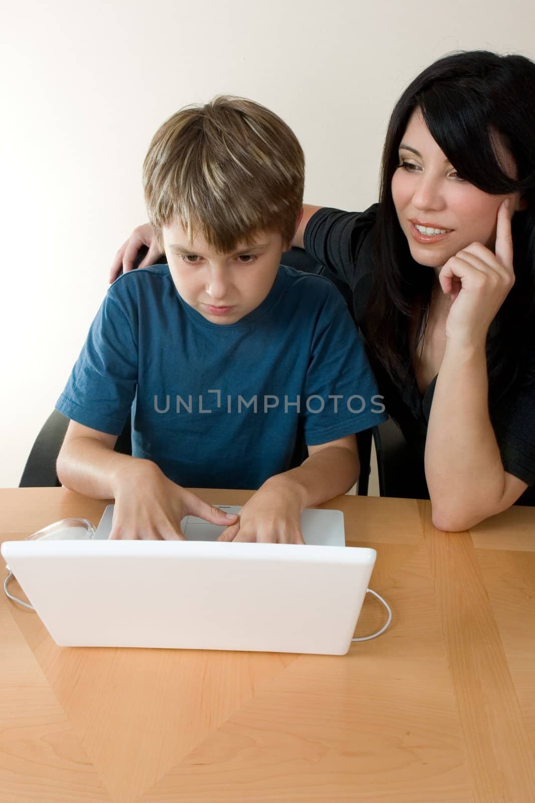 Child using laptop while adult supervises by lovleah