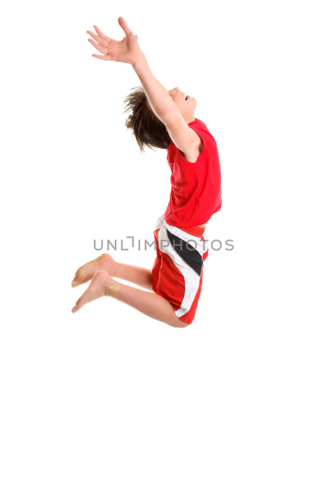 A happy boy leaps mid jump with hands stretched towards the sky.