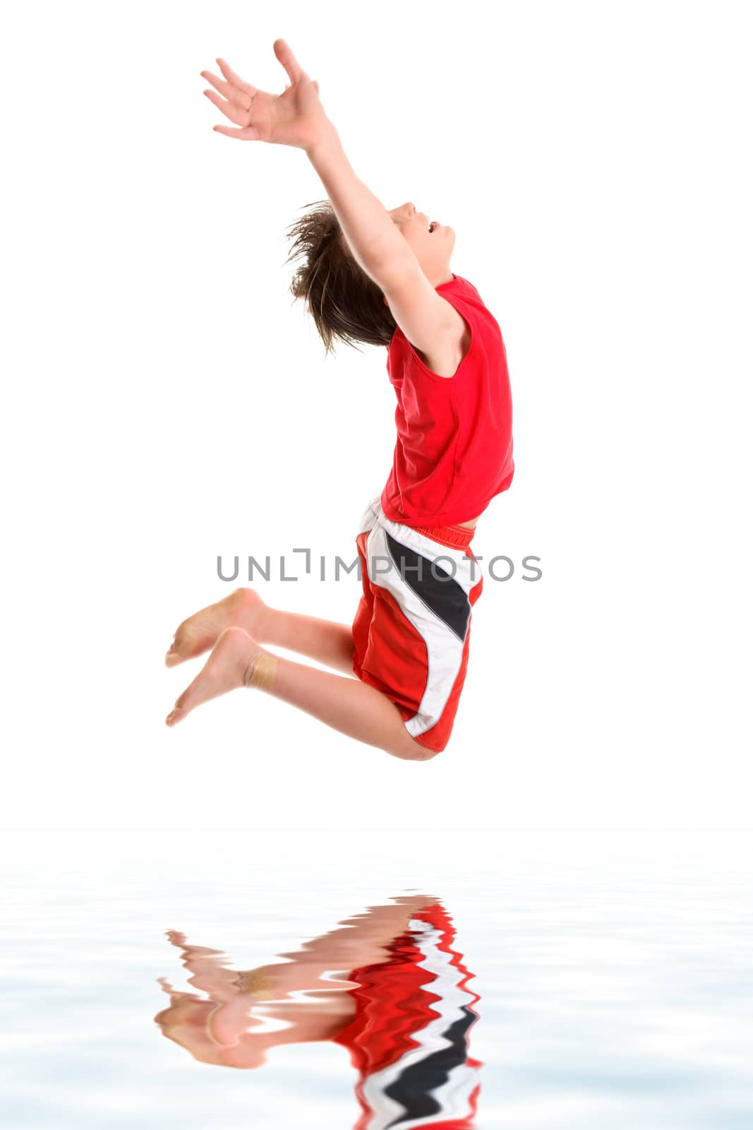 A happy boy leaps mid jump with hands stretched towards the sky.