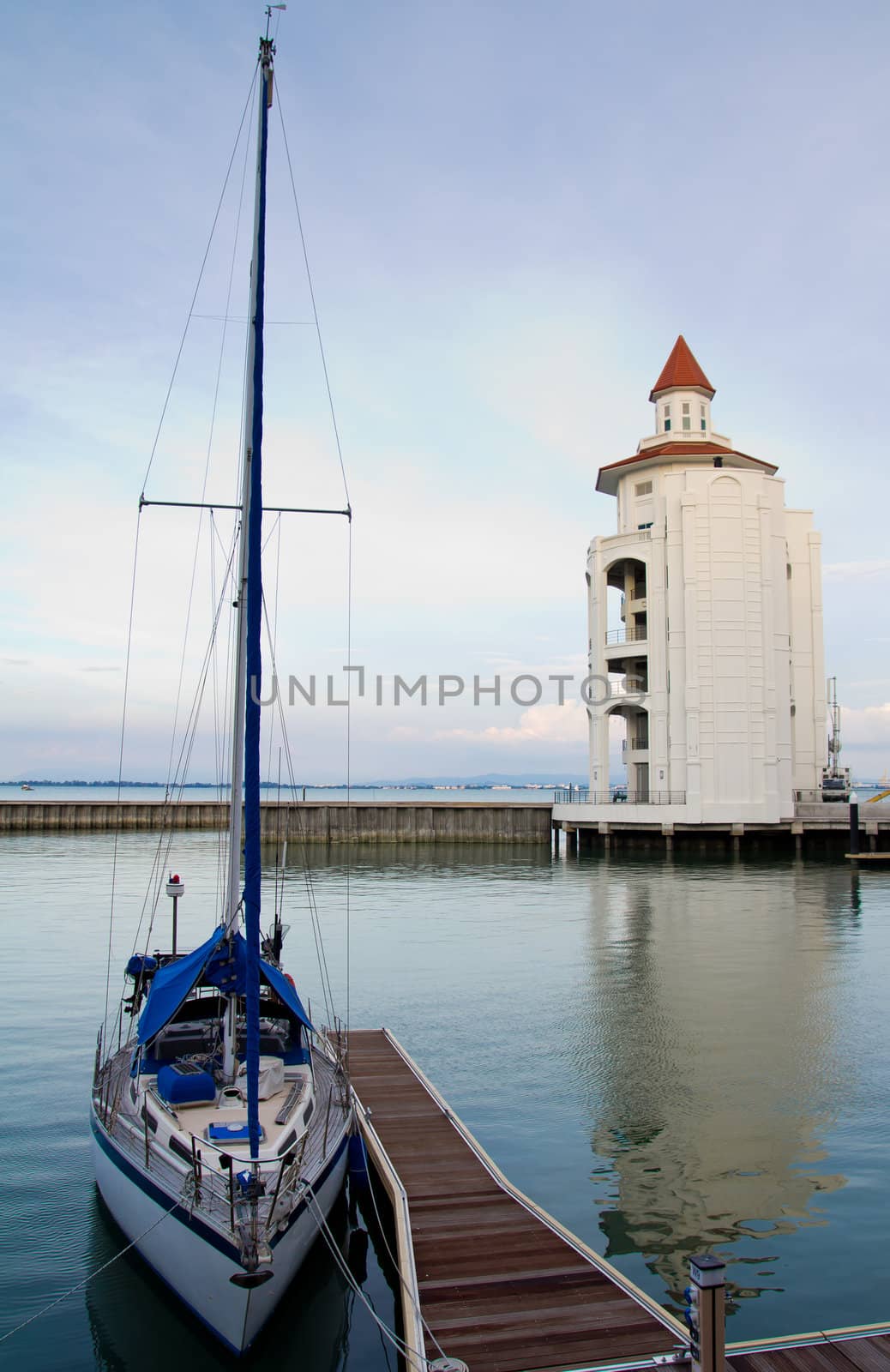 Beautiful yacht docked at jetty with a lighthouse behind