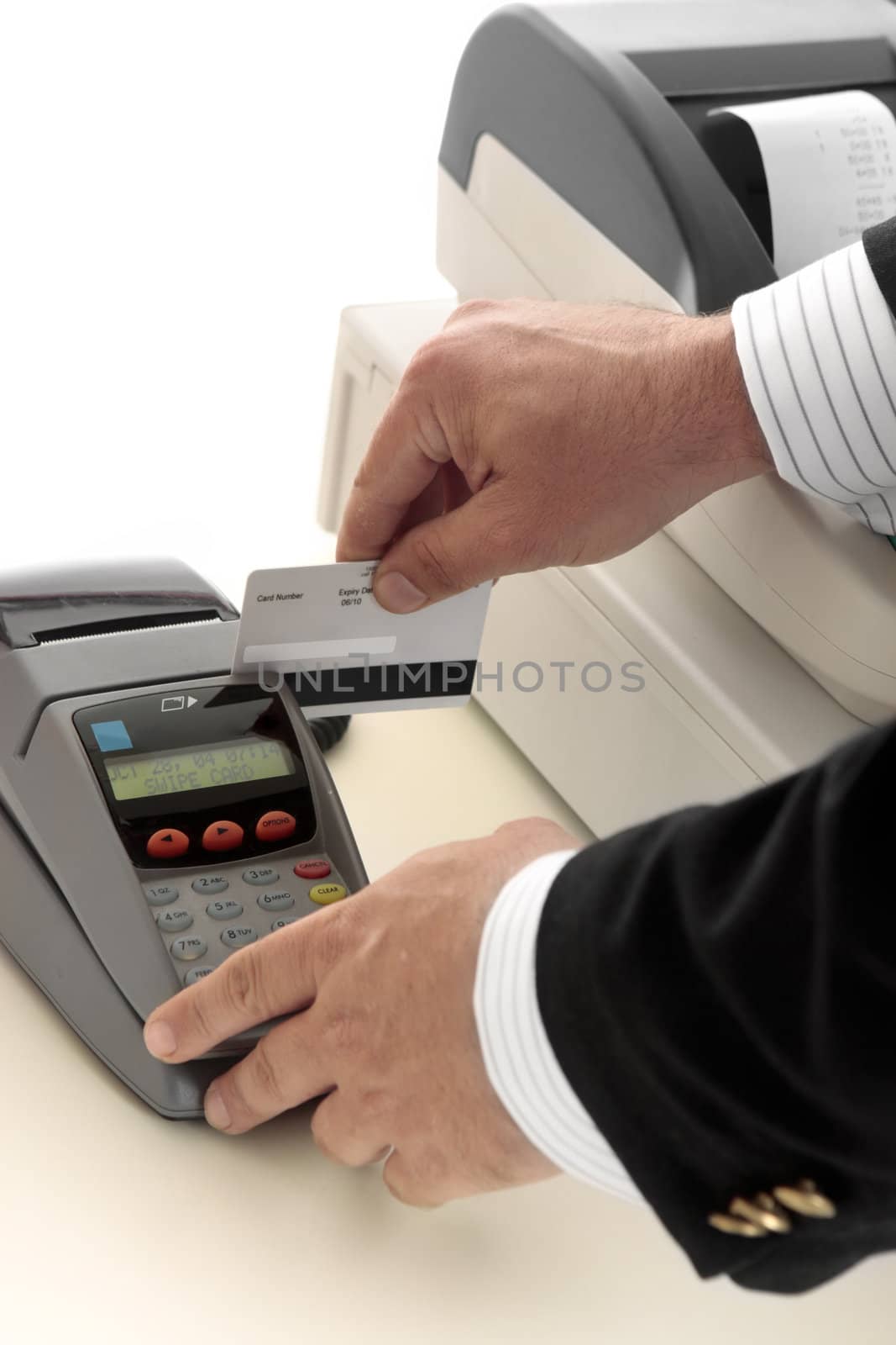 A salesman retailer swipes a credit or debit card through a pos terminal.  Focus to terminal and card.  Details removed from card.