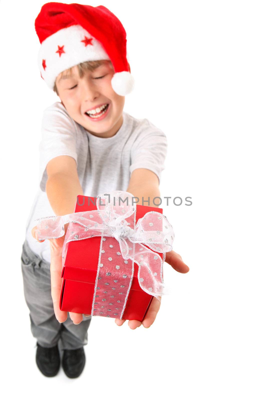 A happy child hands up a present wrapped with silver gauze ribbon in the spirit of Christmas. Selective focus to the gift only.  Boy is not in focus.