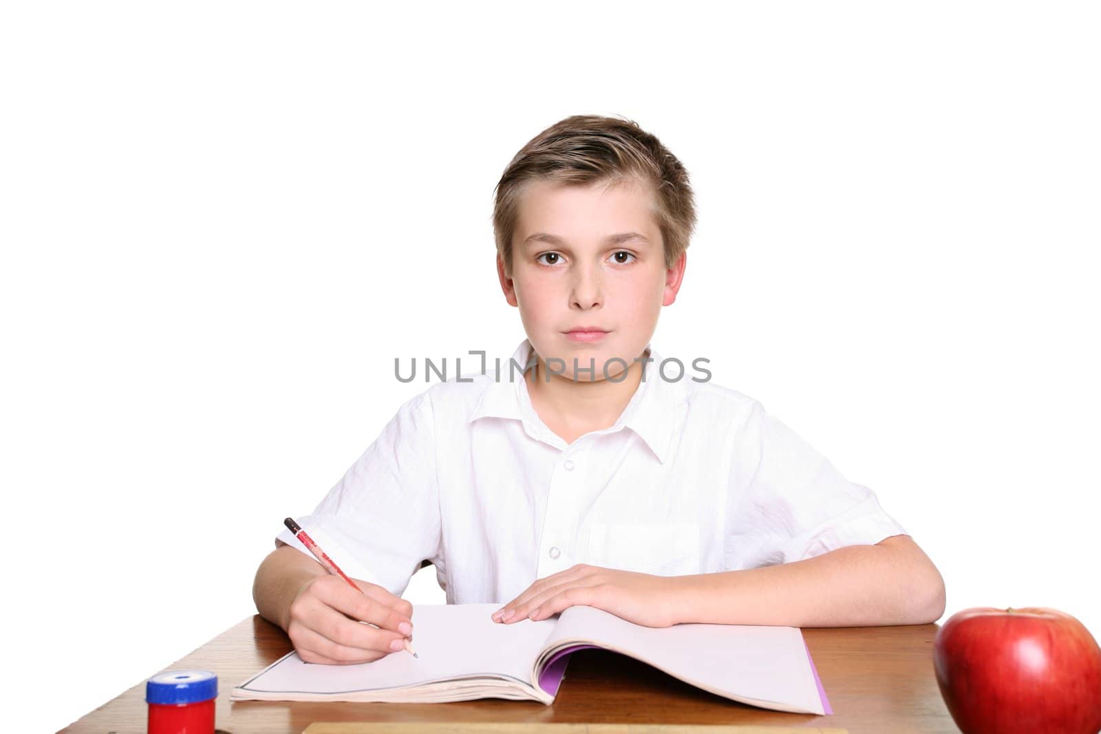 School student sitting at desk with book and pencil doing work.