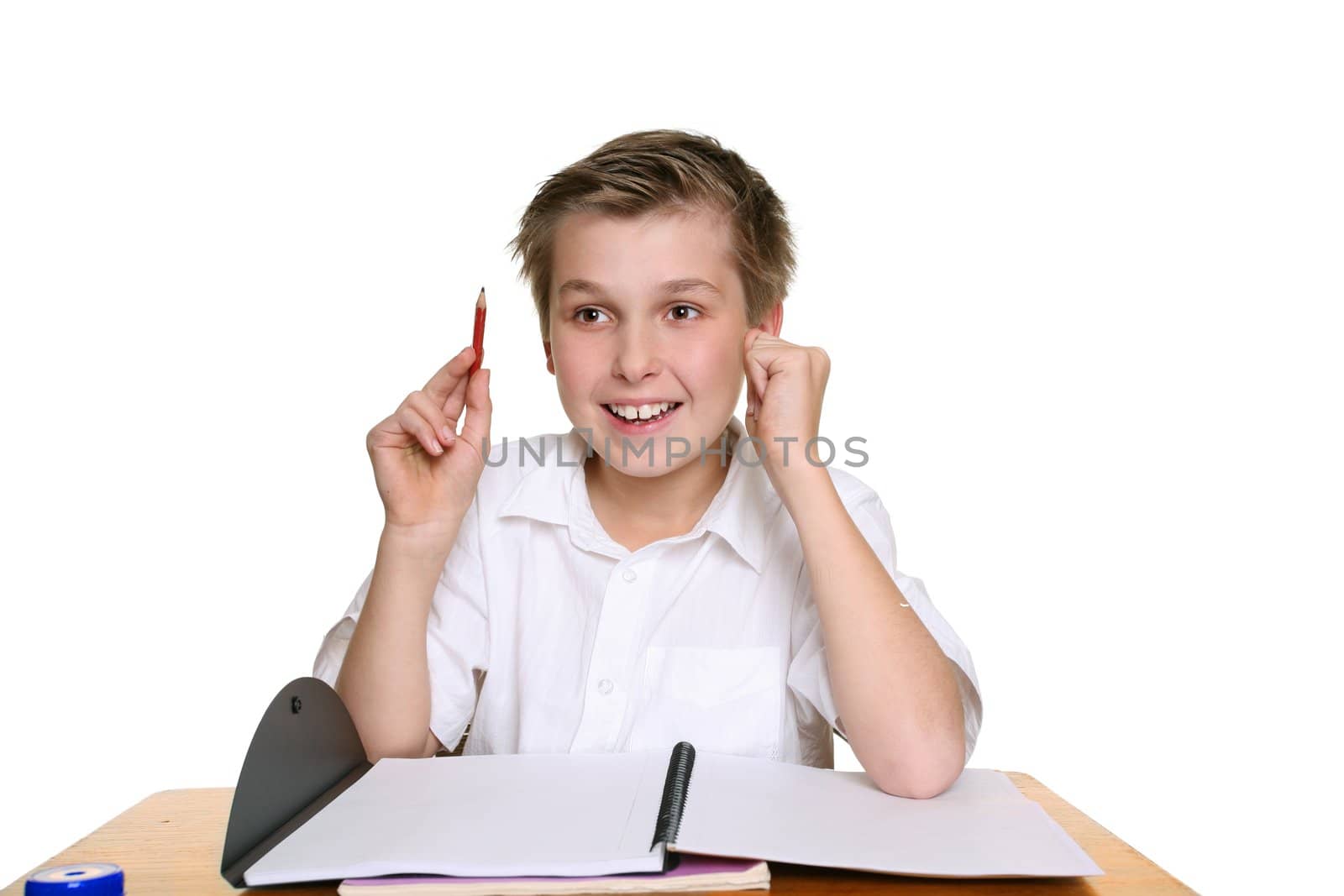 Happy school student sitting at desk with an idea or answer