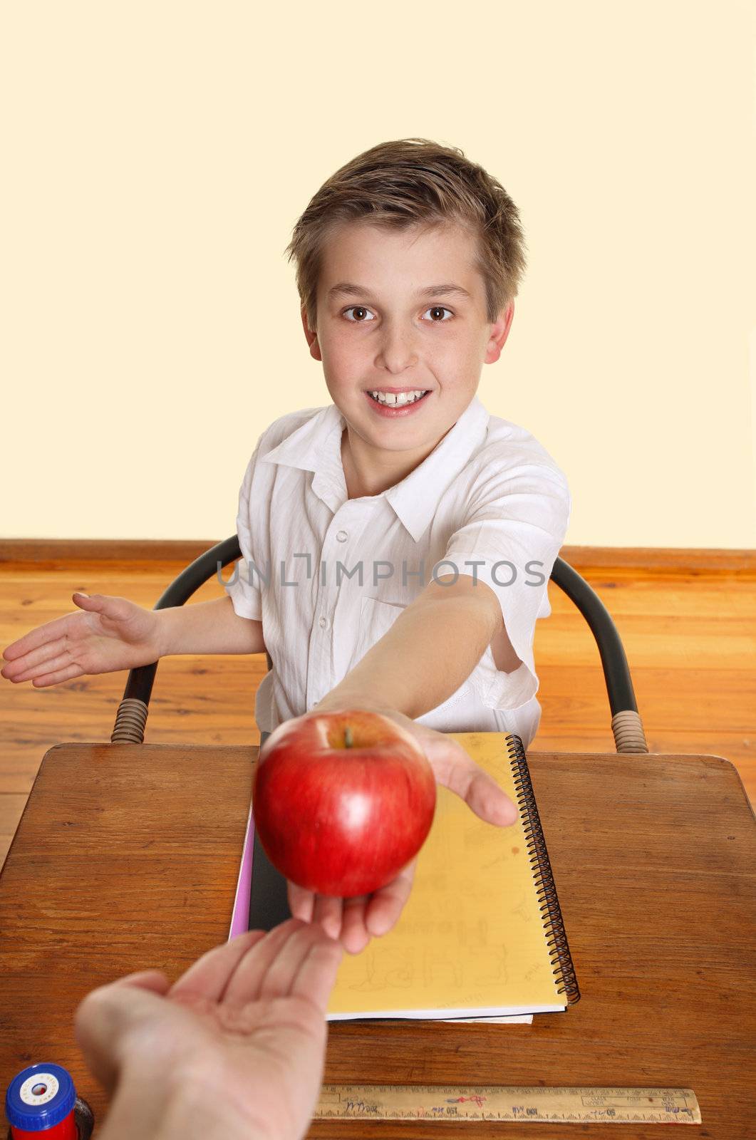 A schoolboy hands his teacher a red apple.